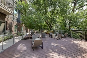 A wooden deck with chairs and trees in the background.